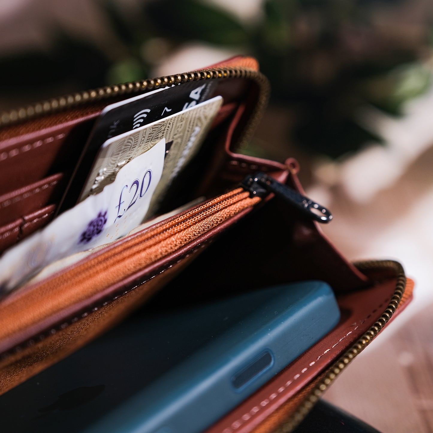 Open brown leather wallet with phone and money on a blurred background