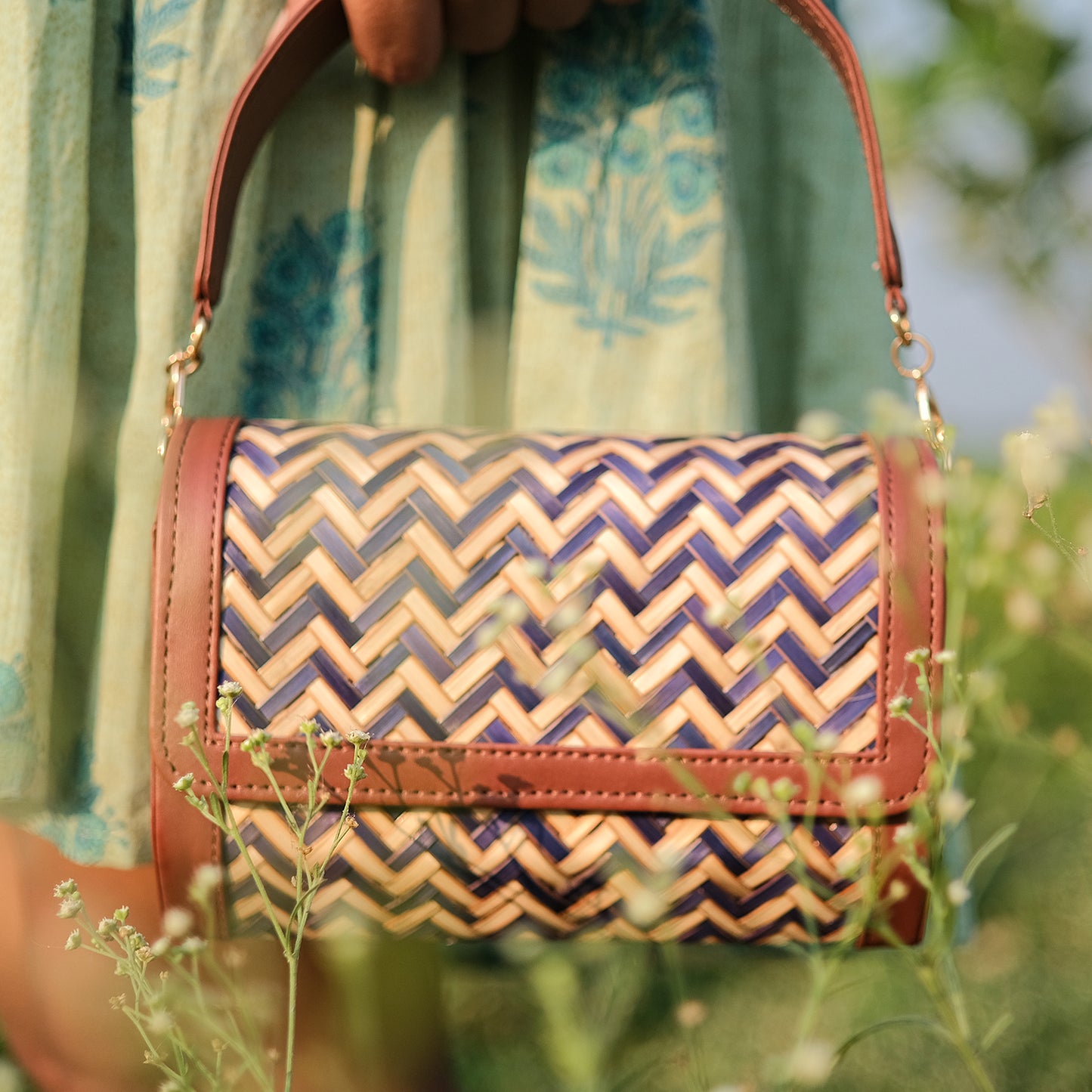 Handbag with chevron pattern held by a person in a natural setting