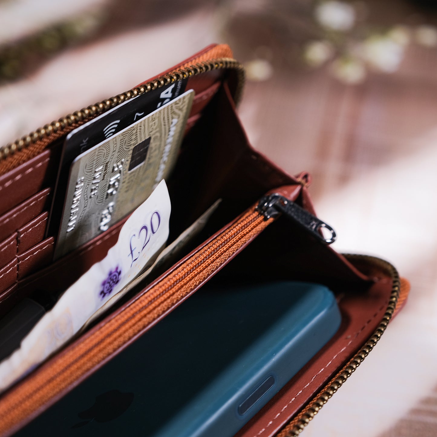 Brown leather wallet with phone and cards on a blurred background