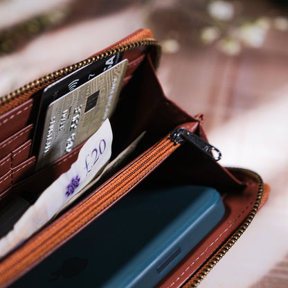 Brown leather wallet with phone and cards on a blurred background