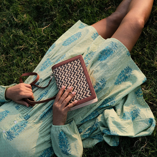 Person sitting on grass holding a patterned bag