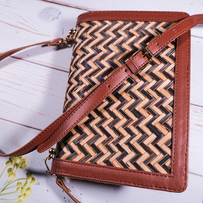 Woven handbag with brown leather accents on a light wooden surface